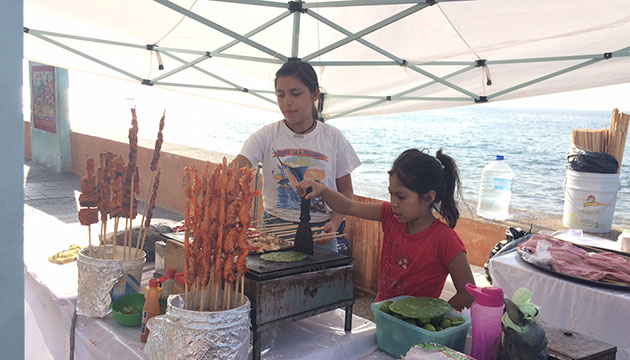 Local girl grilling nopales (cactus) to go with chicken or prawns on skewers at seaside Puerto Vallarta’s popular boardwalk, the Malecon.