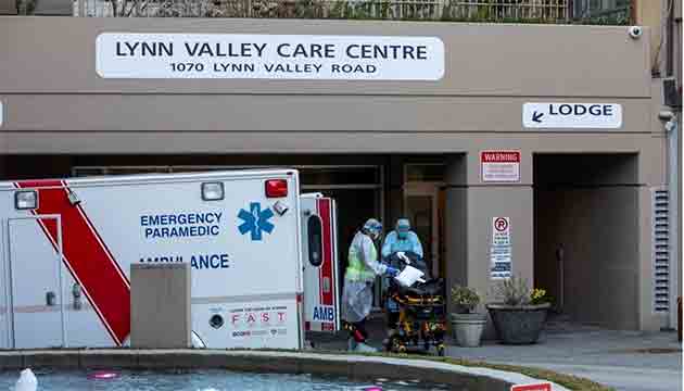 Paramedics wearing full body protective equipment clean a stretcher after responding to a call at the Lynn Valley Care Centre in North Vancouver, British Columbia on Friday, March 20, 2020. (Ben Nelms/CBC)