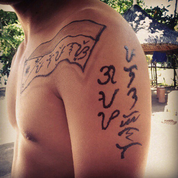 A man with baybayin on his arm and on a Philippine flag design. 